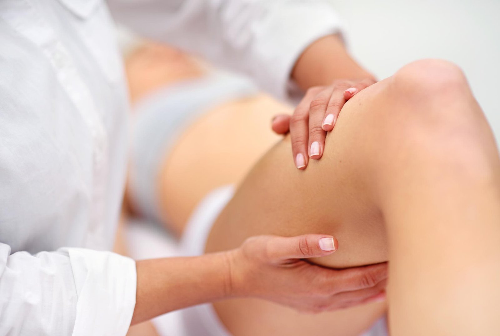 Manuelle Therapie am Knie einer Patientin auf der Behandlungsliege